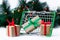 Small grocery basket with gift boxes on Christmas tree background with garland lights. Creative Christmas shopping