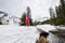 Small group of people sliding on ski on snow-covered bridge and flowing stream under picturesque snow-covered mountains