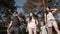 A small group of young people with a guitar stroll through the woods.