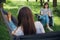 Small group of young woman enjoying conversation at picnic with social distance in summer park. Leisure activity together in new