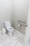 A small half bathroom with gray walls and a toilet with tile floors in a new construction house with a handicap railing