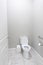 A small half bathroom with gray walls and a toilet with tile floors in a new construction house with a handicap railing