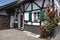 Small half-timber house with flowering red climbing roses and green window shutters