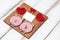 A small handmade panel with a picture of red hearts of a pair of pigs and a small postcard on white wooden background