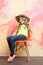 Small happy baby girl in cowboy hat on orange chair