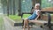 Small happy child girl sitting on a bench resting in summer park.