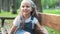 Small happy child girl sitting on a bench resting in summer park