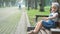 Small happy child girl sitting on a bench resting in summer park