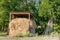 Small hay stack under a canopy with green forest on the background. Autumn harvesting for feeding animals in winter.