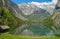 A small house on the shore of the emerald lake Mittersee, surrounded by Alpine peaks.