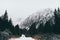 Small human figure walking towards High Tatra mountains through pine tree forest in winter, Slovakia