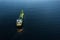 Small illuminated tanker ship with green deck in the dark blue ocean water. Aerial view. Oil and gas transportation and supply.