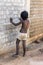 Small indian barefoot boy in worn out poor clothes playing with the wall in the street