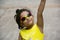 Small Indian girl in a yellow top wearing fancy goggles pointing at something, Pune
