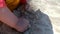 A small infant child digs sand on the beach with his hands. Close-up.