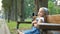 Small irritated child girl sitting alone on a bench in summer park