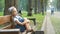 Small irritated child girl sitting alone on a bench in summer park