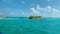 Small island on azure ocean surface against blue cloudy sky