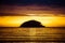Small island in silhouette against a brilliant sunset and lots of colorful reflections