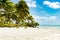 Small island in turquoise clear water with blue sky, white sand, palm trees, Pacific Island, South Pacific Ocean