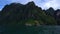 A small islet on the lake and high mountains with jungles on the background.