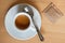 Small italian espresso in white ceramic cup with spoon and packet of sugar isolated on light wood desk from above.