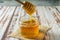 Small jar with pure honey from bees with the honey stick loaded with the honey from the pot on a rustic table