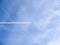 Small jets in distance create chem-trails across blue sky
