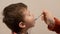 Small kid close up eating from the spoon which is holding by the adult hand. Sick baby eating medicine