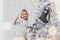 Small kid with funny ponytail is standing near christmas tree, showing thumbs up because her tree is the best.