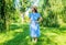 Small kid wear stylish sun hat and checked blue dress on sunny summer landscape, style