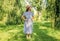 Small kid wear stylish sun hat and checked blue dress on sunny summer landscape, style