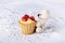 Small knitted teddy bear sitting near mini tartlet