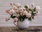 Small  light roses bouquet in the teacup on the wooden table with few lavanda flowers