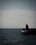 A small lighthouse at the end of a stone pier on a moody summer day