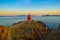 Small lighthouse in front of the sea, over the rocks in beautiful evening sunset