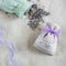 Small linen sack filled with dried lavender decorated with lacework and violet ribbon coqueand and one sachet is opened