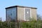 Small local electrical substation building with large front metal double doors and side metal ventilation opening on top of small