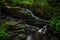 Small Long Exposured Creek With Waterfall In Mystic Forest Near Ullapool In Scotland