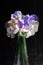 A small, loose arrangement of mixed sweet peas in shades of white and purple against a black background