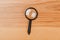 Small magnifying glass on wooden table, search symbol