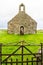 Small medieval Welsh Chapel in field, Anglesey.  Gate in foreground