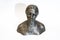 A small metal antique bust of Nadezhda Krupskaya on a white background