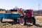 Small mini red tractor stands on a farm yard. Springtime and harvest concept.