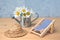 Small miniature lounger , straw hat and watering can with daisies on table