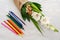 Small modest bouquet consisting of gladiolus, lemon, nuts and colour pencils on a white wooden table as a gift to the school child