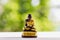 A small monk statue on white wooden table with nature background