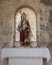 Small monument to a Bishop of Granada with a colorful statue and two candelabaras outside in a neighborhood of Granada, Spain.