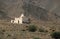 Small Mosque in barren landscape surrounded by stones and bushes, Morocco