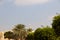 Small Mosque Minaret view between green trees with cloudy blue sky in the background